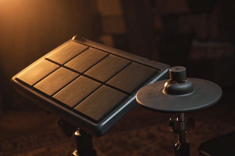 Drum machine con pulsanti consumati e due pad in gomma su un tavolo in sala prove – AI