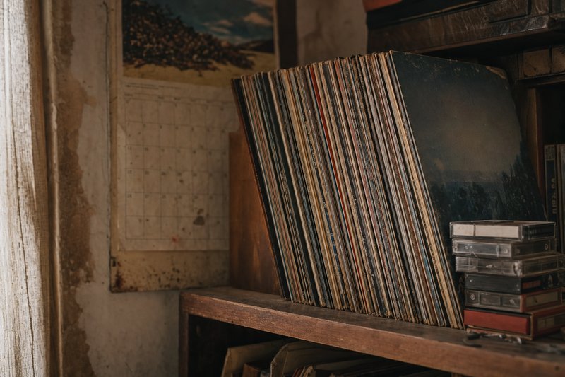 Dischi in vinile e alcune musicassette allineati su uno scaffale di legno – AI